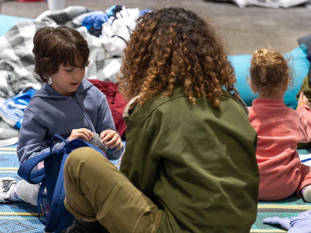 Dual national Israeli German former hostage Naveh Shoham, left, playing with an Israeli soldier near his sister Yahel Neri, after being released, along with their mother. Picture: Israeli Government Press Office / AFP