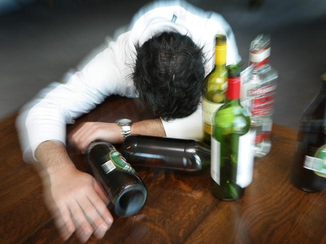 Generic photo of a man surrounded by alcohol bottles. Binge drinking. Drunk.