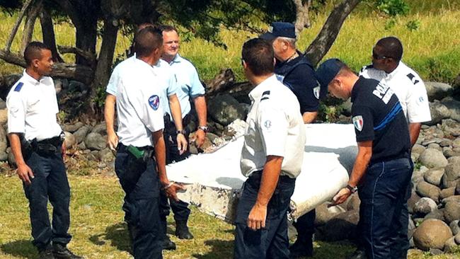 Is it MH370? ... Police and gendarmes carry a piece of debris from an unidentified aircraft found in the coastal area of Saint-Andre de la Reunion, in the east of the French Indian Ocean island of La Reunion. Picture: AFP