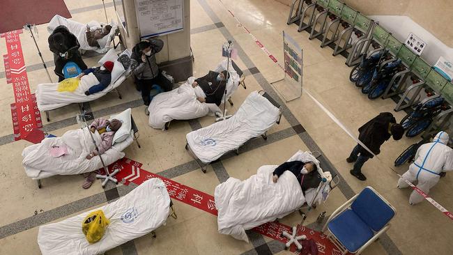 Covid patients lie on hospital beds in the lobby of the Chongqing No. 5 People's Hospital..