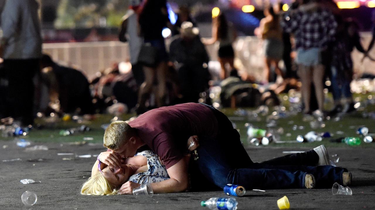 A man shields a woman as others flee the Route 91 Harvest Festival grounds. Picture: AFP