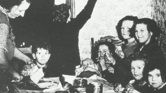 Woman and eight children gathered around a table at meal time. Circa 1935. Picture: F. Oswald Barnett collection, State Library of Victoria