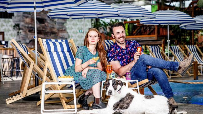 Moon Dog World has an indoor lagoon, retractable roof, greenery and a hidden disco. Ruby Klissarov and Chris Hasted-Adams enjoy cocktails pool side with dog Edie. Picture: Nicole Cleary