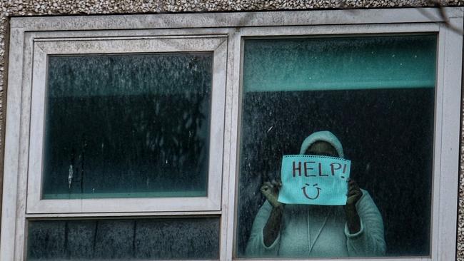 A woman holds a banner at the North Melbourne housing commission flats. Picture: Luis Enrique Ascui