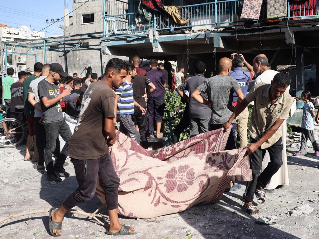 People use a blanket to transport a victim after an Israeli air strike hit a school in Nuseirat. Picture: AFP