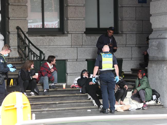 Police talk to a group who were opposite Flinders Street Station. Picture: David Crosling