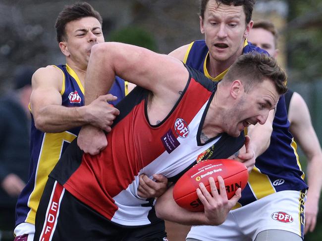 EDFL: West Coburg’s Lynden Dunn can’t escape two Rupertswood tacklers. Picture: Hamish Blair