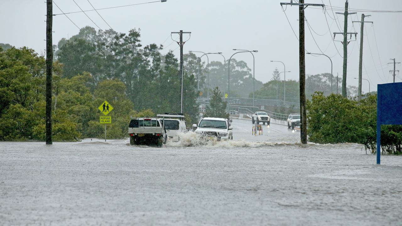 Cars drive through fast-moving floodwaters at Stingray Creek, Laurieton. Picture: Nathan Edwards