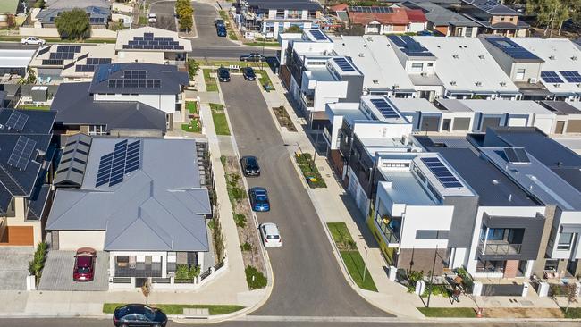 Aerial view looking down on new, modern Adelaide housing development with mixed house & architectural styles: single level houses, townhouses, construction site, green space, established suburb & city in background. Picture: iStock/BeyondImages