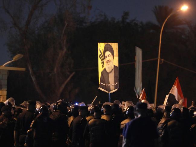 A demonstrator holds a picture of Hassan Nasrallah during a protest vigil near the suspension bridge leading to Baghdad's Green Zone. Picture: AFP.