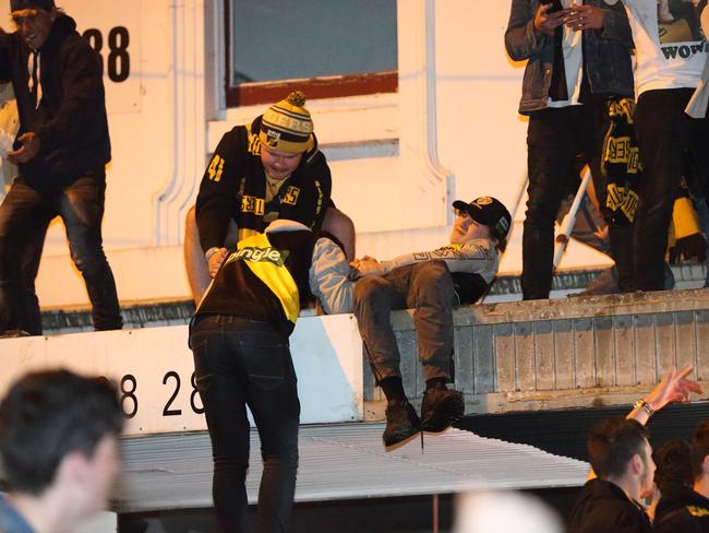 Fans help others onto shop roofs on Swan St. Picture: Patrick Herve