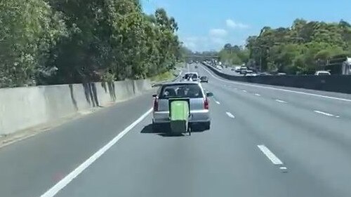 A video shows a car towing a wheelie bin on the M1 in a 110km/h zone at Worongary, Gold Coast.