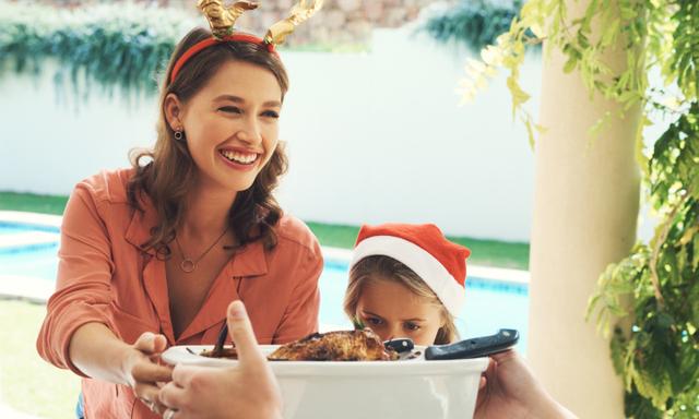 Shot of a beautiful young mother handing over a bowl of food at a Christmas lunch party
