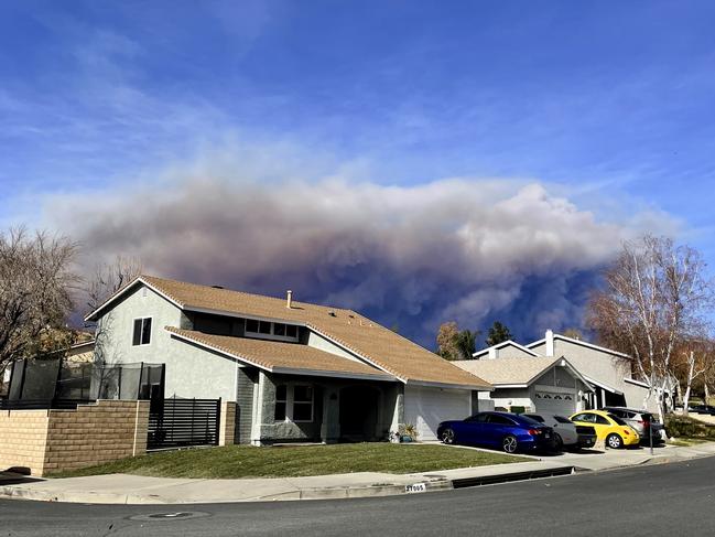 A large plume of smoke caused by the Hughes fire rises from Castaic Lake as seen from a neighbourhood of Santa Clarita. Picture: AP