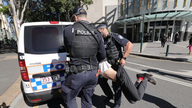 Police officers prepare to put Herbert in the back of a police vehicle.