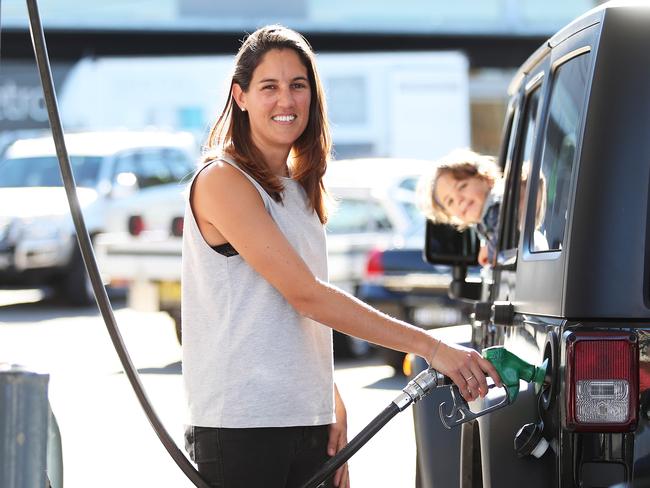 Jess Walker of Newtown fills up her car with petrol as her son Lachlan watches on at Bargain Petrol station in Erskineville, Sydney. This station has the cheapest petrol around. Picture: Brett Costello