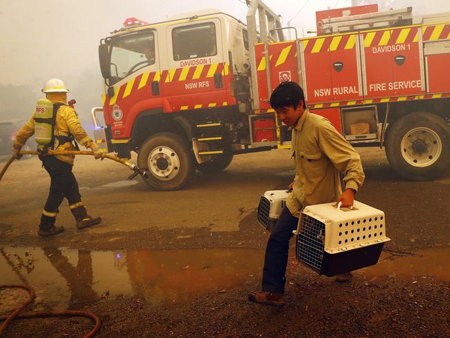 A man carrying animals makes a last minute escape as crews battle to save the tiny Southern Highlands town. Picture: Sam Ruttyn