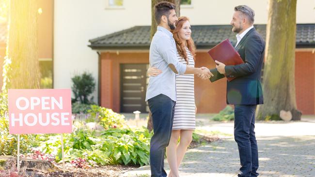 A real estate agent welcomes potential buyers to an open house.