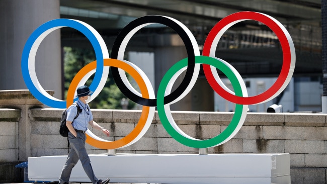 TOKYO, JAPAN - JULY 19: A man wearing a face mask walks past the Olympic Rings ahead of the Tokyo 2020 Olympic Games on July 19, 2021 in Tokyo, Japan. (Photo by Toru Hanai/Getty Images)
