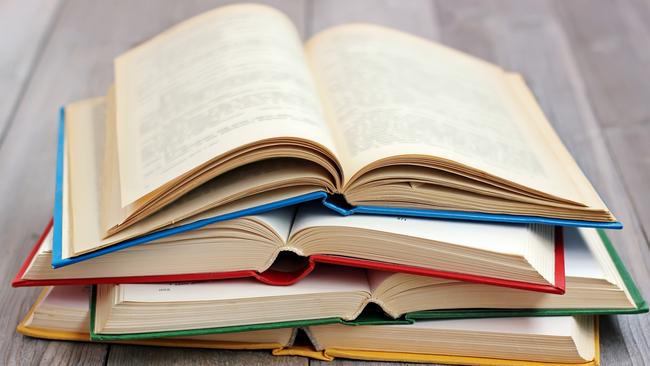 Four open books in the colored cover on the table made of boards.A stack of books in the colored covers on the table with a red tablecloth. Still life with books. iStock image