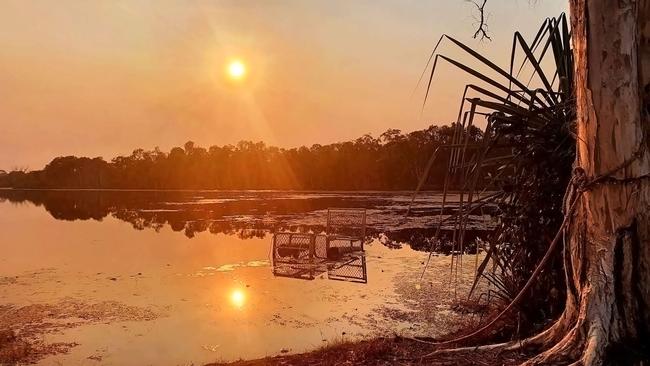 The sun bids farewell in a serene sunset over the calm waters of Jabiru Lake. Picture: Roger Orford