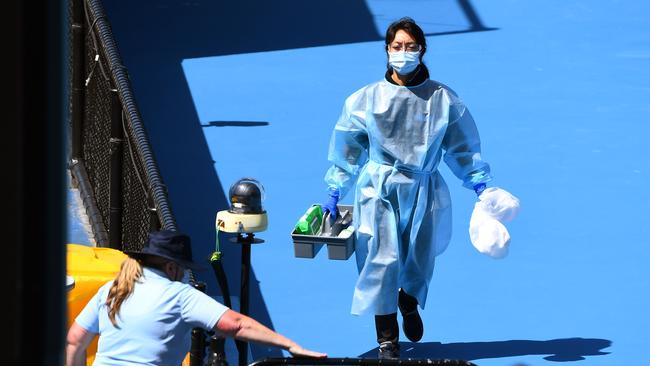 A cleaner leaves an Australian Open court after preparing it for the next group of tennis players for a practice session in Melbourne yesterday. Picture: AFP