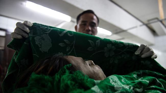 Embalmer Alejandro Ormeneta displaying the body of an alleged drug dealer gunned down by unidentified men that he just finished embalming in the morgue of Veronica Memorial Chapel in Manila. Picture: AFP / Noel Celis.