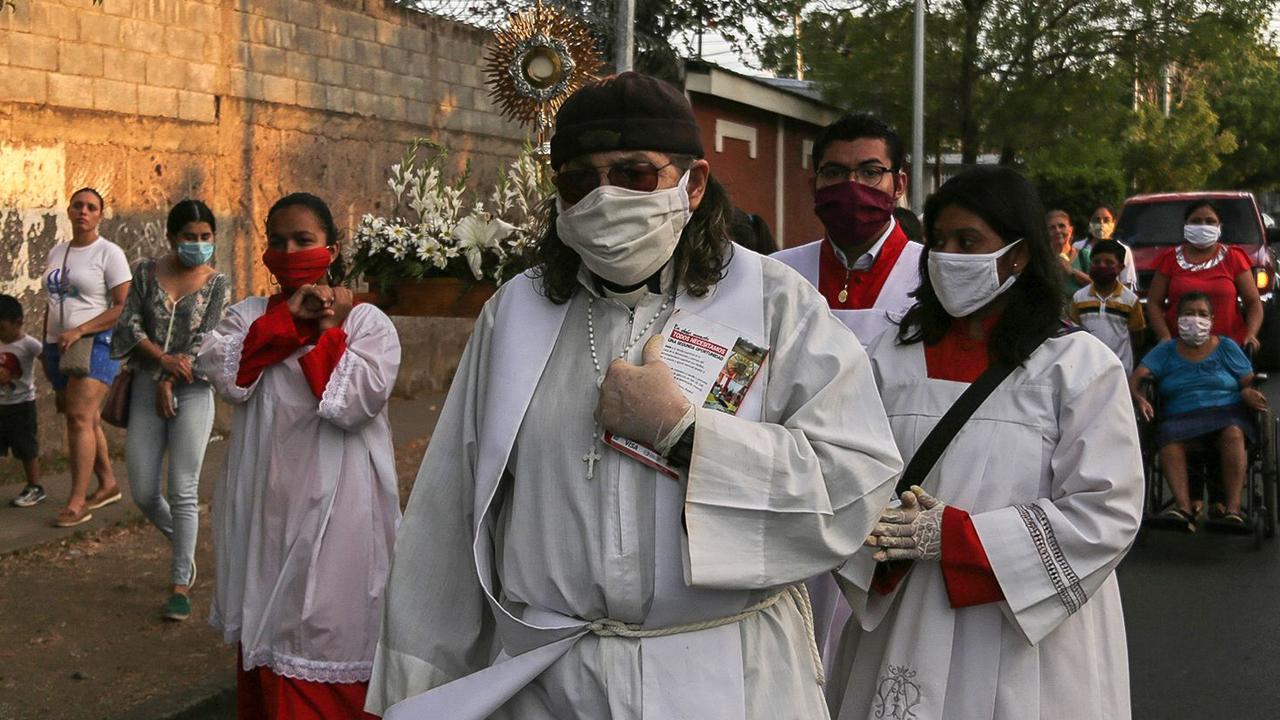 Priest Jose Luis Montoya (C) wears a face mask as a precautionary measure against the spread of the new coronavirus, COVID-19, while walking with faithful in the procession of the Penitential Way of the Cross making stations in the homes of sick people, in Managua.