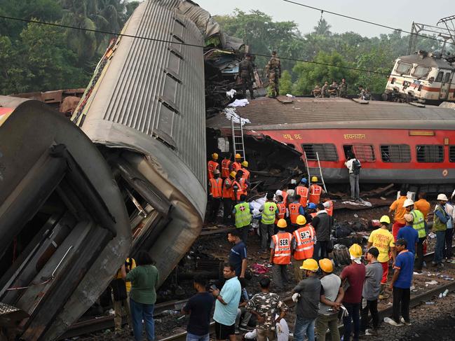 TOPSHOT - Rescue workers gather around damaged carriages at the accident site of a three-train collision near Balasore, about 200 km (125 miles) from the state capital Bhubaneswar in the eastern state of Odisha, on June 3, 2023. At least 288 people were killed and more than 850 injured in a horrific three-train collision in India, officials said on June 3, the country's deadliest rail accident in more than 20 years. (Photo by DIBYANGSHU SARKAR / AFP)