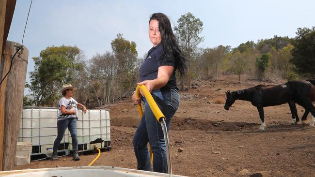 The Tetlow family one of many at Canungra who no longer have access to water from the Canungra treatment plant and the fuelling station. Emily Spurr fills water trough for the horses with Julie Tetlow in background at their property. Picture Glenn Hampson