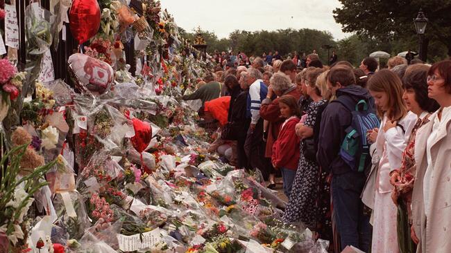 Crowds of people lined up to leave flowers and read messages left by others at Kensington Palace in 1997. Picture: AP Photo/Santiago Lyon