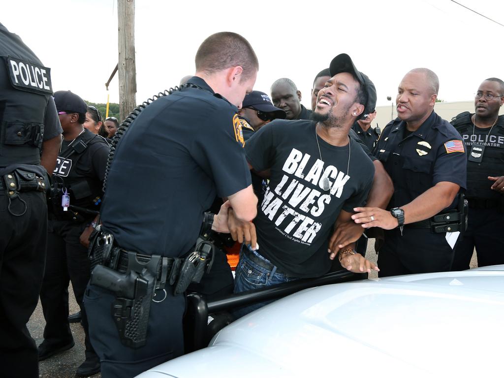 An African American protester is arrested by police.