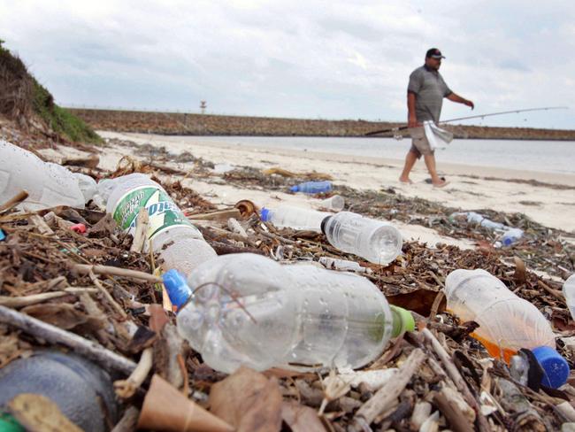 A fisherman walks along dirty beach at Kyeemagh in Sydney, which is covered with plastic bottles and other rubbish, 06 Jan 2006. litter refuse disposal