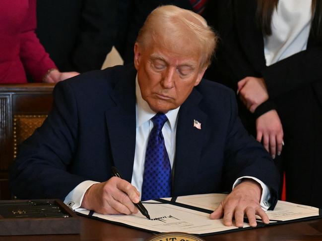 US President Donald Trump signs the Laken Riley Act in the East Room of the White House in Washington, DC, January 29, 2025. The Laken Riley Act -- which mandates the detention of undocumented immigrants charged with theft-related crimes -- is named for a 22-year-old student murdered by a Venezuelan man with no papers who was wanted for shoplifting. (Photo by PEDRO UGARTE / AFP)