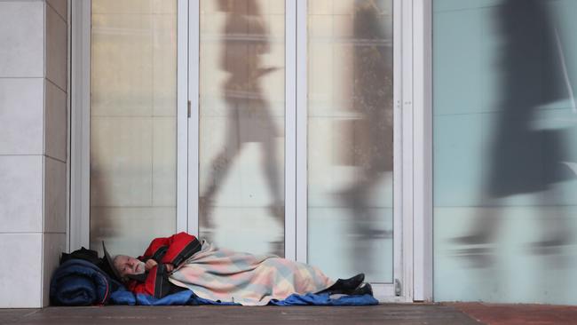 A homeless man finds shelter from the rain in the city. Picture: Tait Schmaal