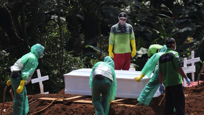 Grave diggers wearing raingear as protection bury a coronavirus victim in Jakarta on Thursday. Picture: Getty Images