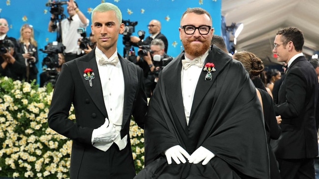 Sam Smith attending alongside their partner, designer Christian Cowan. The couple coordinated their outfits, both accessorised with red rose boutonnières. Picture: Getty