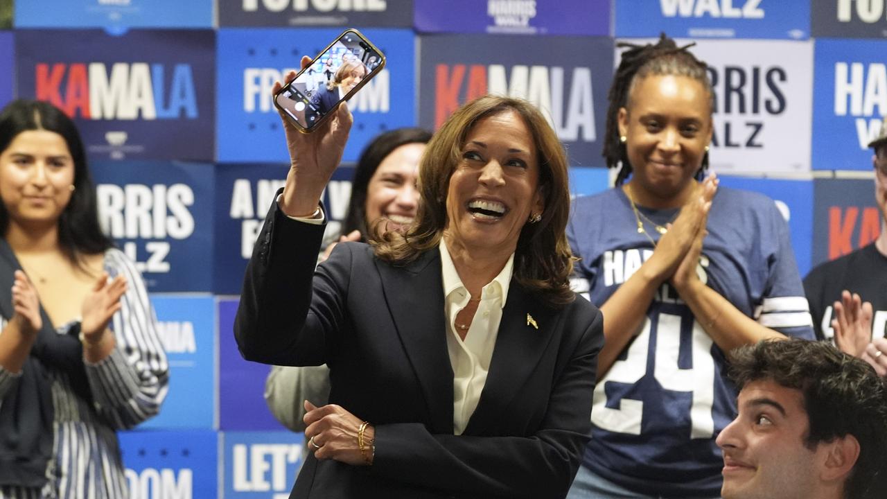 Kamala Harris holds up a phone as she phone banks with volunteers at the DNC headquarters on election day in Washington. Picture: AP Photo/Jacquelyn Martin