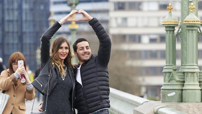 TOPSHOT - People pose for photographs on Westminster Bridge in central London on March 23, 2017 after the bridge reopened to traffic following its closure during the March 22 terror attack. Britain's parliament reopened on Thursday with a minute's silence in a gesture of defiance a day after an attacker sowed terror in the heart of Westminster, killing three people before being shot dead. Sombre-looking lawmakers in a packed House of Commons chamber bowed their heads and police officers also marked the silence standing outside the headquarters of London's Metropolitan Police nearby. / AFP PHOTO / NIKLAS HALLE'N