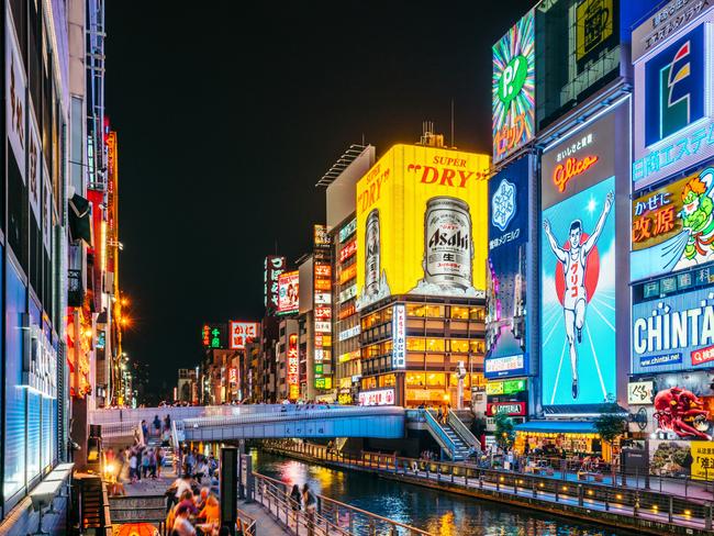 Tourists and locals walk below the famed advertisements lining Dotonbori Canal at. The district is one of Osaka's primary tourist destinations. Photo - istock Escape 10 Nov 2024