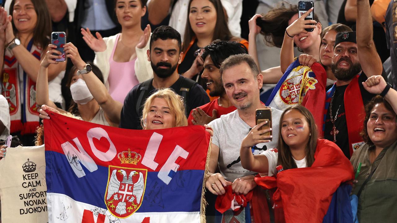 Spectators hold Serbian flags to celebrate with Djokovic.