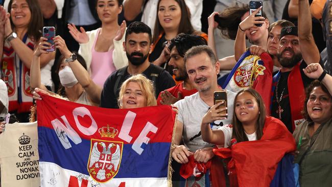 Spectators hold Serbian flags to celebrate with Djokovic.