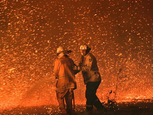 (FILES) This file picture taken on December 31, 2019 shows firefighters struggling against strong winds in an effort to secure nearby houses from bushfires near the town of Nowra in the Australian state of New South Wales. - Australia's unique wildlife is in retreat as it reels from bushfires, drought, human activity and global warming, according to a 