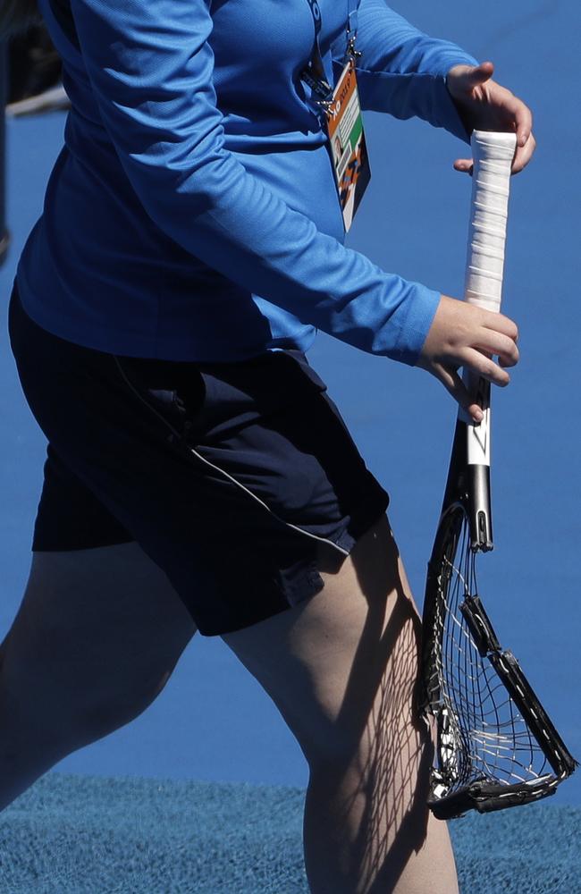 A court attendant takes the smashed racket away. Picture: Mark Schiefelbein/AP