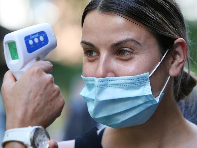 SYDNEY, AUSTRALIA - SEPTEMBER 24: A healthcare worker conducts a temperature test as people arrive to check in at the Sonic Healthcare COVID-19 Vaccination hub in the CBD on September 24, 2021 in Sydney, Australia. COVID-19 restrictions have eased for people in NSW who are fully vaccinated, with up to five people allowed to gather outdoors. The eased restrictions only apply to people who don't live in the 12 local government areas of concern and have received two doses of a COVID-19 vaccine. NSW Premier Gladys Berejiklian has outlined a roadmap out of the current statewide lockdown, with a range of restrictions to be eased when 70% of the state's eligible population are fully vaccinated. These freedoms will only be restored for the fully vaccinated. (Photo by Lisa Maree Williams/Getty Images)