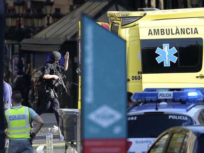 An armed policeman arrives in a cordoned-off area after a van ploughed into the crowd, killing at least 13 people. Picture: AFP/Josep Lago