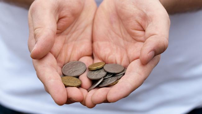 A caucasian man holds out some Australian coins; poor money generic hands