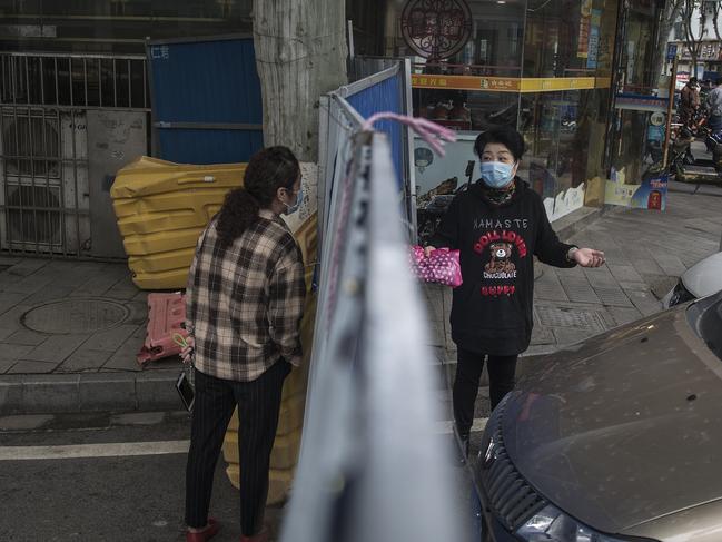 Residents chat over a makeshift barricade built to control entry and exit to a residential compound on Wuhan, Hubei Province, China, believed to be where COVID-19 originated. Picture: Getty