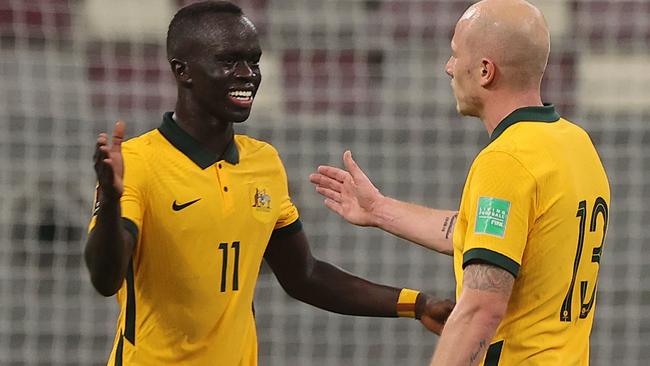 Australia's midfielder Aaron Mooy (R) and Australia's forward Awer Mabil celebrate their win in the 2022 Qatar World Cup Asian Qualifiers football match between Australia and Oman, at the Khalifa International Stadium in the Qatari capital of Doha, on October 7, 2021. (Photo by KARIM JAAFAR / AFP)