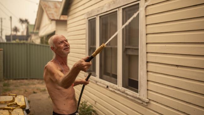 Lee Bateman hoses down his home in Bega. Picture: Sean Davey.